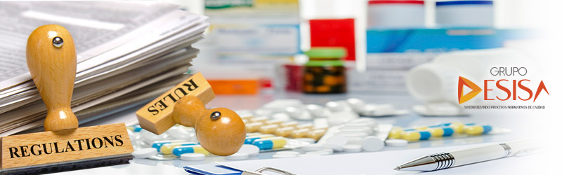 Sellos de madera "Regulations" y "Rules" junto a blísteres de medicamentos y el logotipo de Grupo DESISA